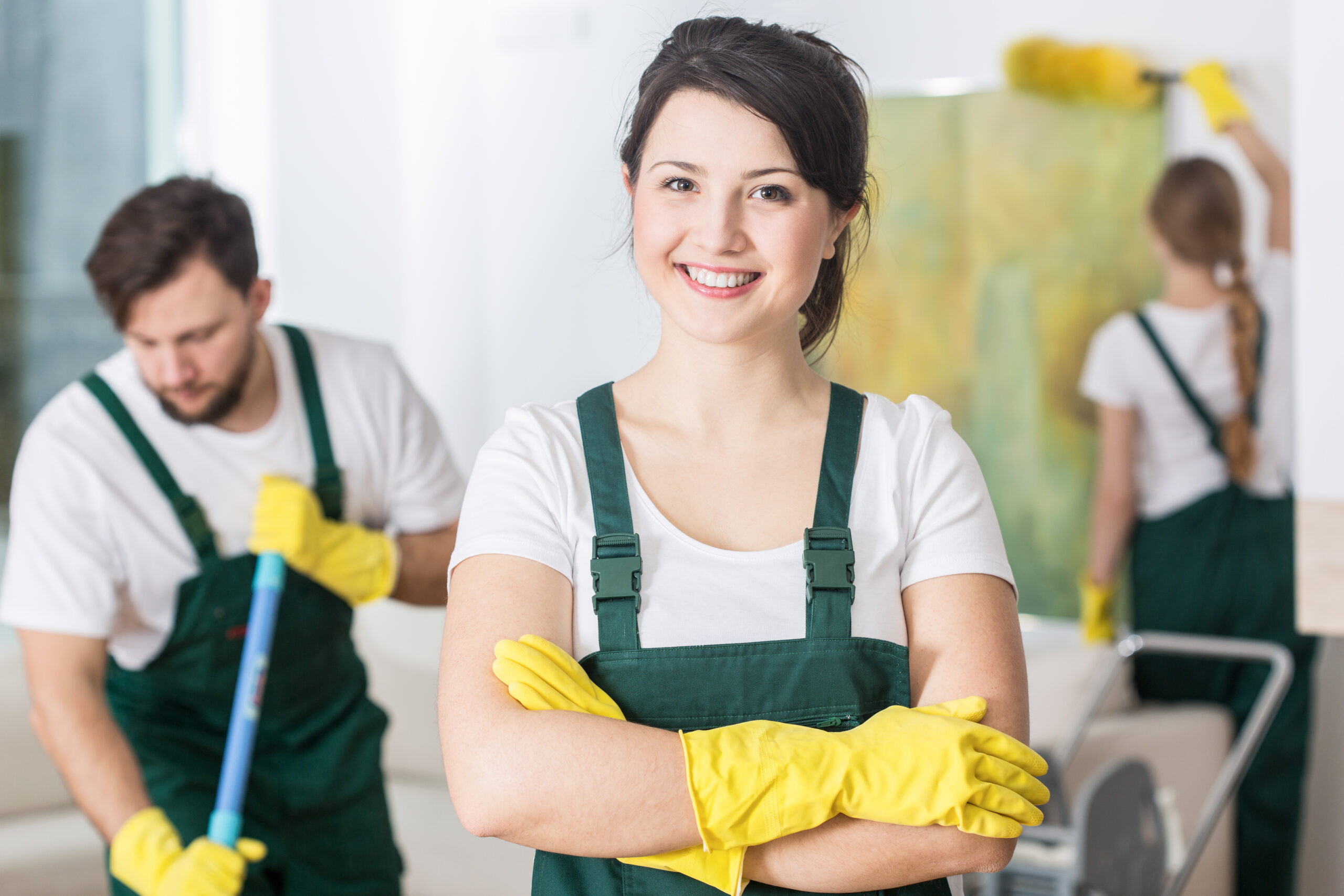 Smiling cleaning lady in uniform and yellow rubber gloves